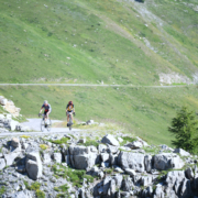 ciclisti su strada di montagna in provincia di Cuneo, valle Grana, colle Fauniera. Ambiente roccioso e verde.