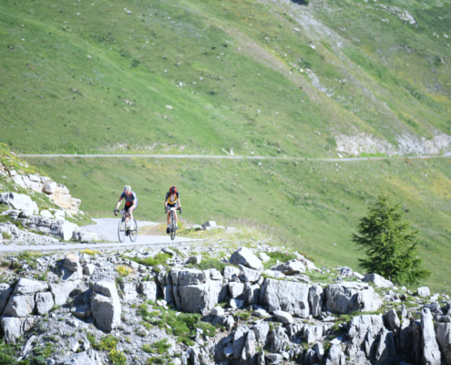 ciclisti su strada di montagna in provincia di Cuneo, valle Grana, colle Fauniera. Ambiente roccioso e verde.